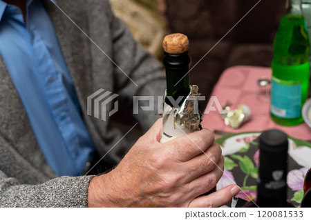 Senior man opening champagne bottle at festive dinner table Senior man opening champagne bottle at festive dinner table 120081533