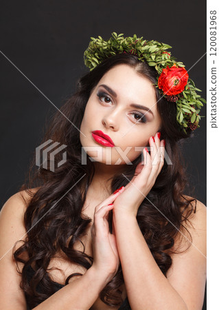 Cheerful healthy female model with shiny hair, make-up and spring flower on black background 120081968