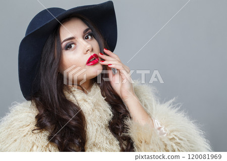 Glorious woman with red lips make-up and long wavy hair wearing blue hat  120081969