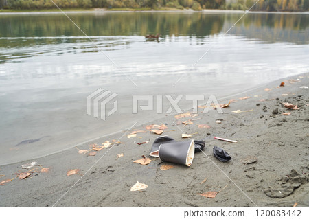 Pollution on riverbank with discarded cups and leaves illustrating environmental Pollution on riverbank with discarded cups and leaves illustrating environmental 120083442