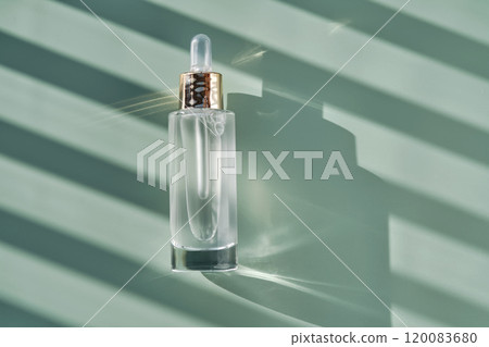 Bottle of cosmetic serum with pipette on green background with shadow stripes. Bottle of cosmetic serum with pipette on green background with shadow stripes. 120083680