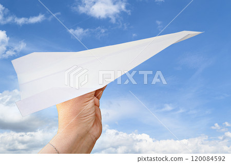 Woman hand holding paper plane on background of blue sky with white clouds 120084592