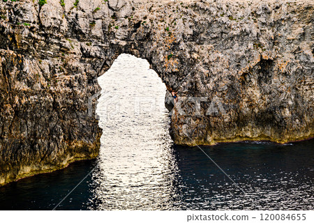 Spectacular sunset at Pont den Gil, Cala Corbetar in Ciutadella, Menorca, Balearic Islands. Peculiar natural formation in the form of an arch Spectacular sunset at Pont den Gil, Cala Corbetar in Ciutadella, Menorca, Balearic Islands. Peculiar natural formation in the form of an arch 120084655