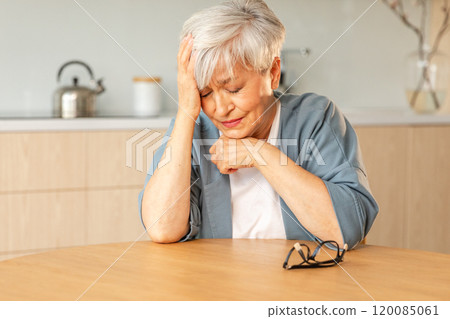 Headache pain. Unhappy middle aged senior woman suffering from headache sick rubbing temples at home. Mature old senior grandmother touching temples experiencing stress Woman feeling pain hurt in head 120085061