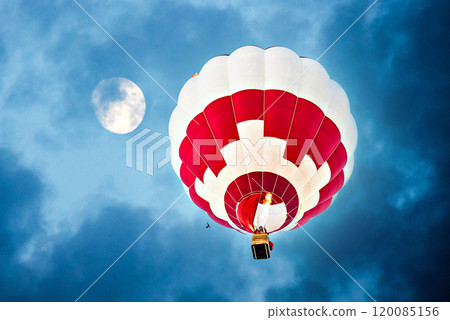 Colorful hot air balloon flying under a night sky with a full moon 120085156