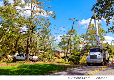 An elevated platform holds worker performing maintenance on transformer attached to wooden pole. 120085688
