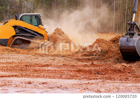 In course of earthworks, small earthmoving tractor is leveling ground during construction In course of earthworks, small earthmoving tractor is leveling ground during construction 120085720