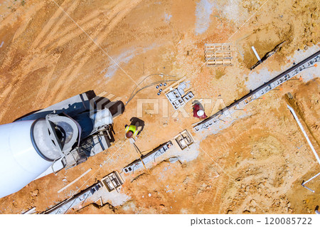 Preparation of construction site is concrete mixer truck is laying concrete along prefabricated foundation forms 120085722