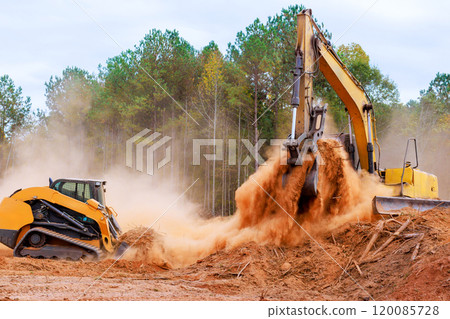 An earthmoving small mini tractor is leveling ground during construction during earthworks 120085728