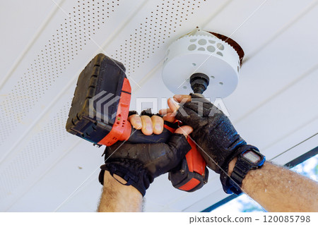 Preparing ceiling for installation of a new light fixture with using cordless drill 120085798