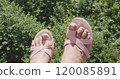 Woman playfully swinging her feet while wearing stylish pink sandals 120085891