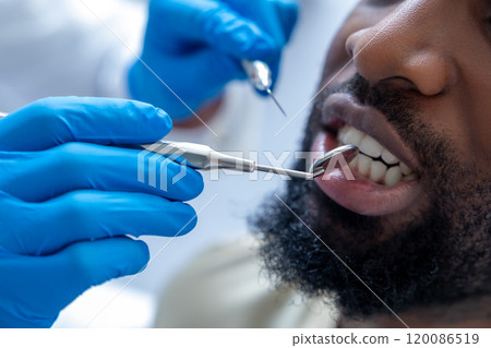 Professional dentist in modern office checking patient's gums with dental tool Professional dentist in modern office checking patient's gums with dental tool 120086519