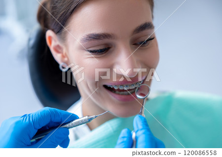 Beautiful woman having examination at dental office while dentist checking her braces 120086558