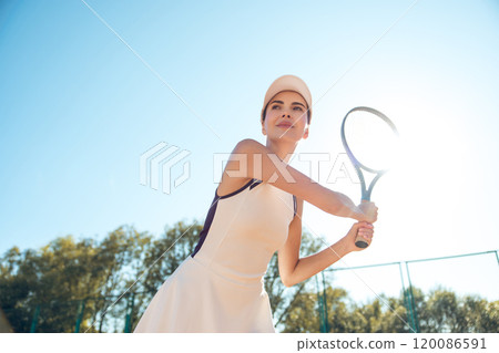 Young female tennis player looking concentrated and focused while playing on the courts 120086591