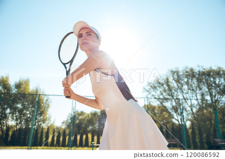Young female tennis player looking concentrated and focused while playing on the courts 120086592