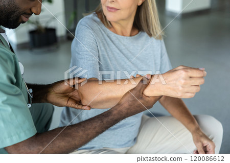 Doctor checking the joints of a female patient in a rehabilitation center 120086612