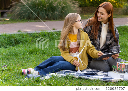 Teacher guiding little girl on tablet while discussing wind energy and environment Teacher guiding little girl on tablet while discussing wind energy and environment 120086707