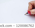 A close-up view of a hand holding a pencil poised above a blank sheet of paper ready for writing or drawing in natural light 120086762
