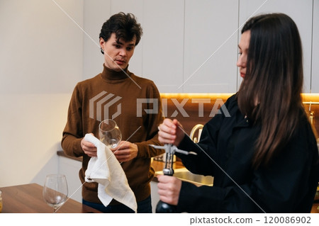 Friends enjoying wine preparation together in a modern kitchen setting 120086902