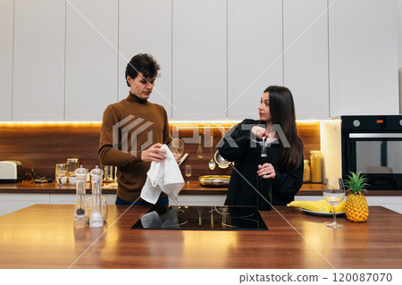 Young couple preparing drinks in a modern kitchen during evening gathering Young couple preparing drinks in a modern kitchen during evening gathering 120087070