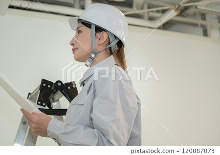 A female engineer in work clothes performing building maintenance 120087073