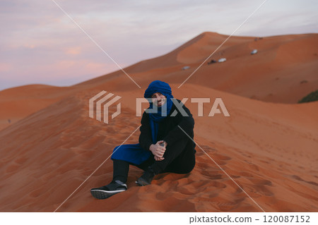 Man with a Berber scarf on the top of a dune at Sahara desert 120087152