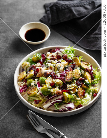Salad of roasted brussels sprouts with lettuce, quinoa, nuts and cranberries in a plate 120087310
