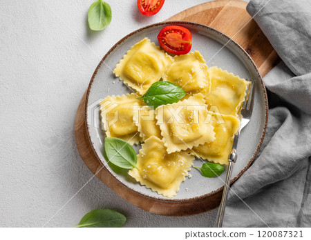 Homemade ravioli pasta with cheese, tomatoes and basil in a plate on a wooden board 120087321