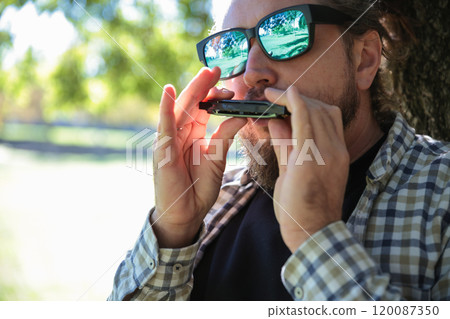 Man with Dreadlocks Ponytail in Sunglasses Playing Harmonica, Mouth Organ Man with Dreadlocks Ponytail in Sunglasses Playing Harmonica, Mouth Organ 120087350