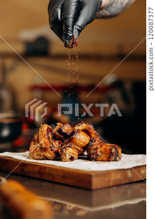 Chef adds spices to grilled ribs on a wooden board, creating a flavorful and aromatic dish Chef adds spices to grilled ribs on a wooden board, creating a flavorful and aromatic dish 120087377