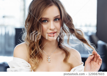 Young woman with curly hair poses elegantly in a modern indoor setting Young woman with curly hair poses elegantly in a modern indoor setting 120087603