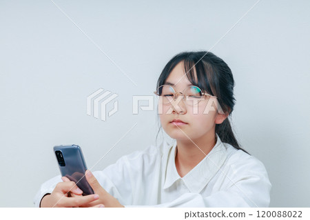 A girl falls asleep while holding a smartphone 120088022