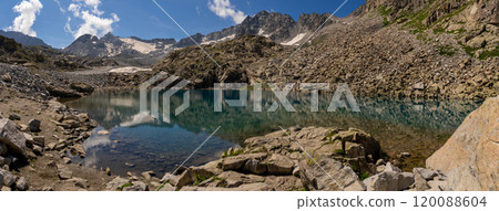 Crystal-Clear Alpine Lake with Rocky Shore and Snow-Capped Peaks 120088604