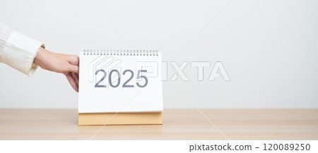 Business woman hand change 2025 Year Calendar on table in office background. countdown, Happy New Year, Resolution, Year End and New Start and Goals Plan Action Concept 120089250