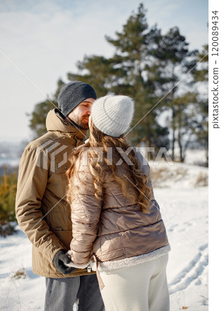Portrait of romantic couple having fun on winter walk. Man and woman kissing. Family wearing warm jacket and knitted hats. Portrait of romantic couple having fun on winter walk. Man and woman kissing. Family wearing warm jacket and knitted hats. 120089434