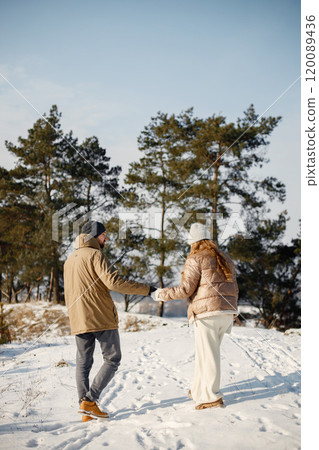 Portrait of romantic couple having fun on winter walk. Man and woman holding hands. Family wearing warm jacket and knitted hats. Portrait of romantic couple having fun on winter walk. Man and woman holding hands. Family wearing warm jacket and knitted hats. 120089436