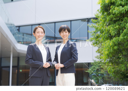 Two women smiling in front of an office Two women smiling in front of an office 120089621