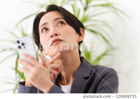 A young woman wearing a business suit operating a smartphone Business image 120089735
