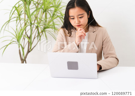 一位穿著西裝、操作筆記型電腦的年輕女性的商業形象 120089771