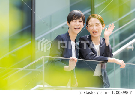 Two women smiling in front of an office Two women smiling in front of an office 120089967