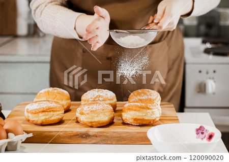 Woman prepares fresh donuts with jam in home kitchen. Cooking traditional Jewish Hanukkah sufganiyot. Woman prepares fresh donuts with jam in home kitchen. Cooking traditional Jewish Hanukkah sufganiyot. 120090020