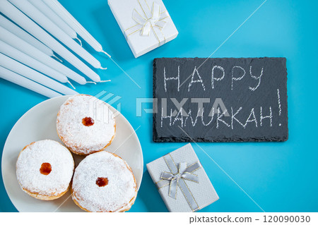 Happy Hanukkah. Jewish dessert sufganiyot donuts on blue background. Symbol of religious Judaism holiday. Inscription on chalk board. Happy Hanukkah. Jewish dessert sufganiyot donuts on blue background. Symbol of religious Judaism holiday. Inscription on chalk board. 120090030