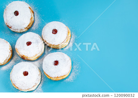 Symbols of Jewish religious holiday Hanukkah. Traditional dessert donuts sufganiyot on blue background. Symbols of Jewish religious holiday Hanukkah. Traditional dessert donuts sufganiyot on blue background. 120090032