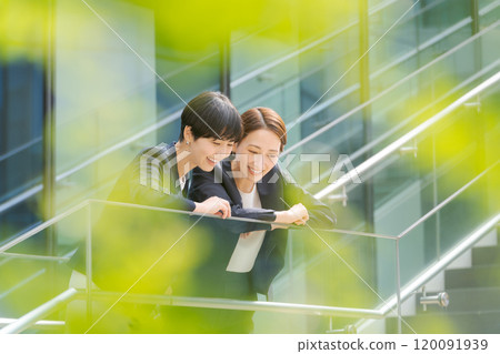 Two women smiling in front of an office 120091939