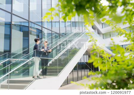 兩個女人站在辦公室前面說話 120091977