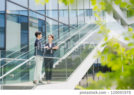 Two women standing and talking in front of an office Two women standing and talking in front of an office 120091978