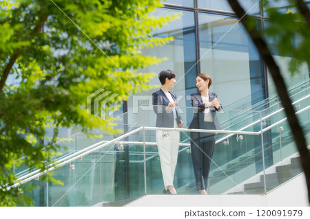 Two women standing and talking in front of an office Two women standing and talking in front of an office 120091979