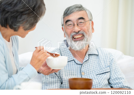 Senior woman feeding her husband 120092110