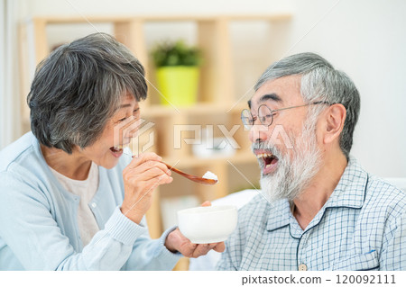 Senior woman feeding her husband 120092111
