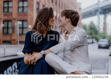 A Romantic Couple Posing Together Against the Iconic Bridge Backdrop in the Evening Light A Romantic Couple Posing Together Against the Iconic Bridge Backdrop in the Evening Light 120092236